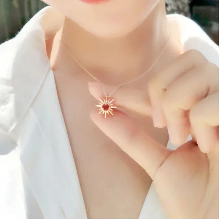 Garnet Sunburst Pendant Necklace worn at the neckline in a close-up