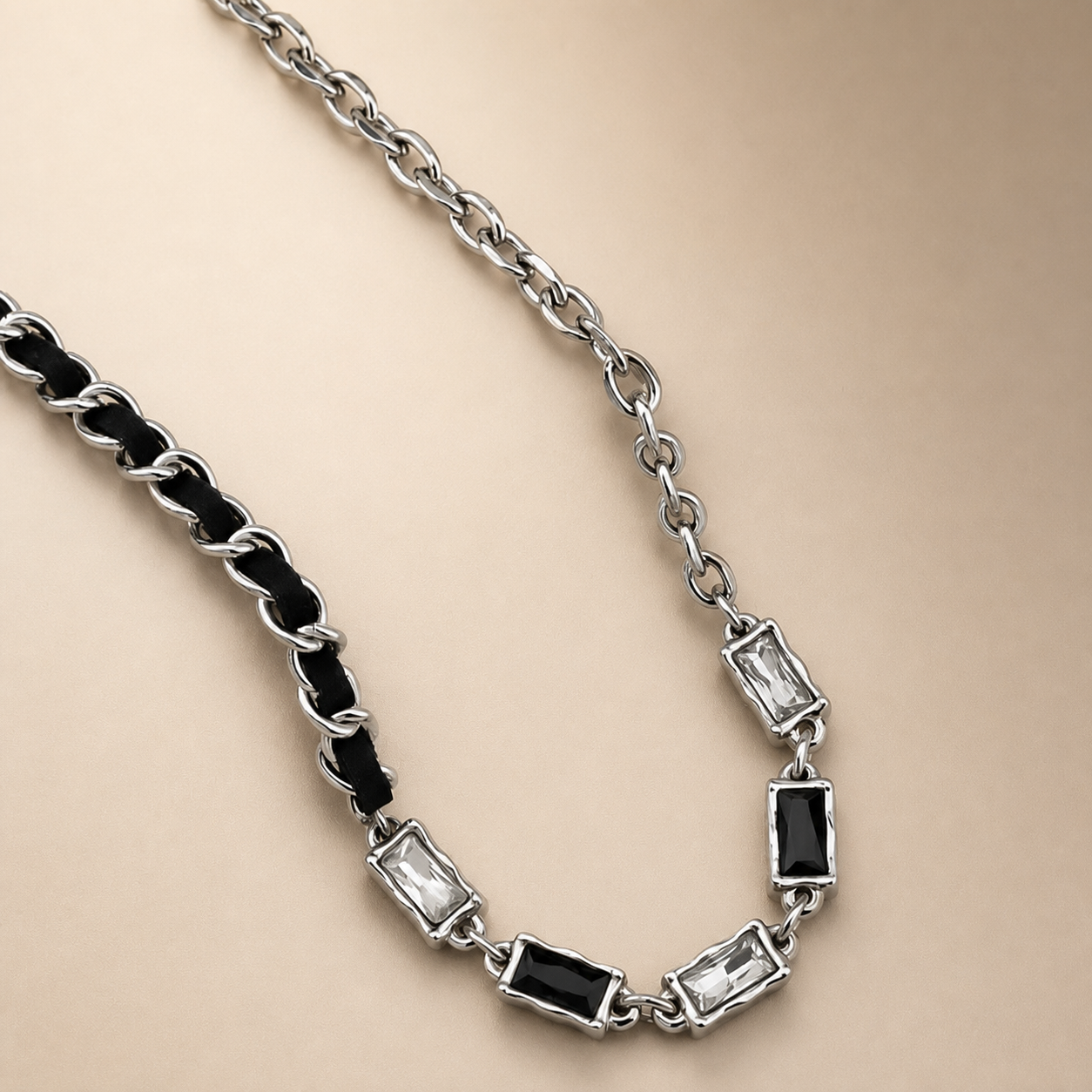 Black and clear gemstone inlaid silver-tone necklace on a warm champagne background