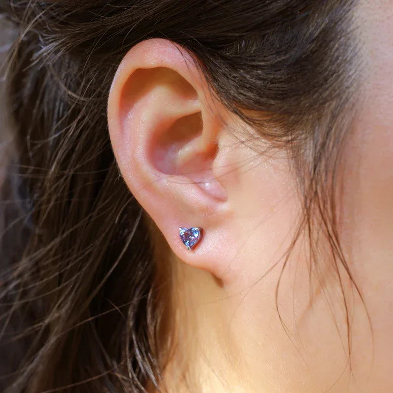 Heart Alexandrite stud earrings, shown worn on an ear for scale