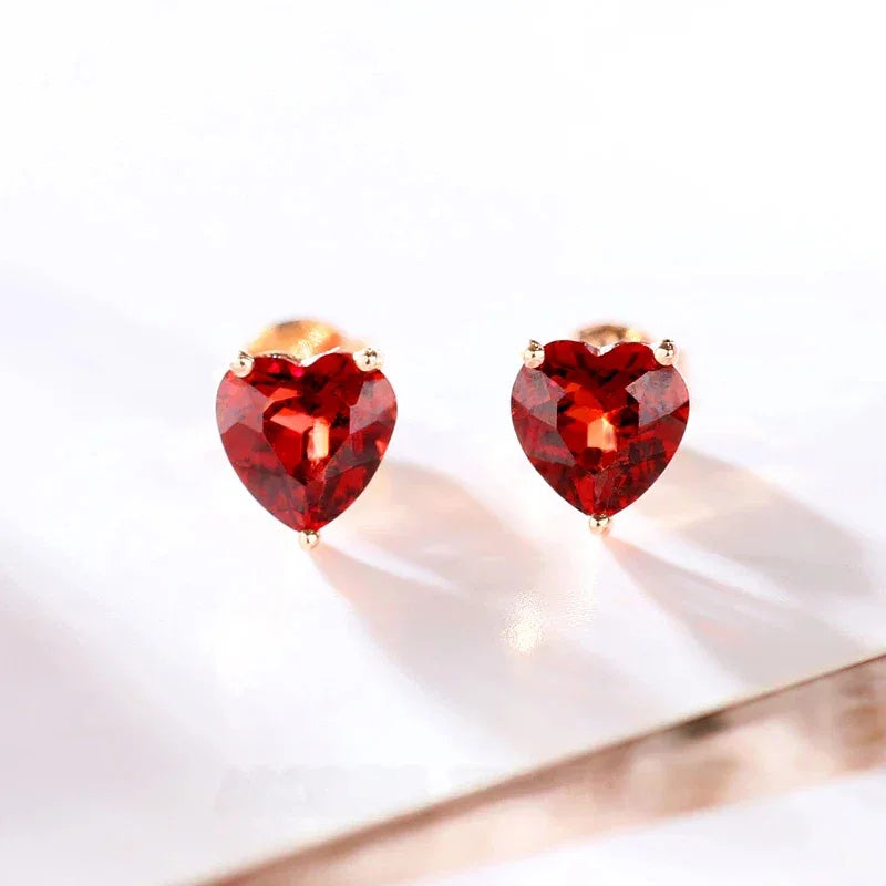 Heart-Cut Garnet Stud Earrings side view held between the fingers