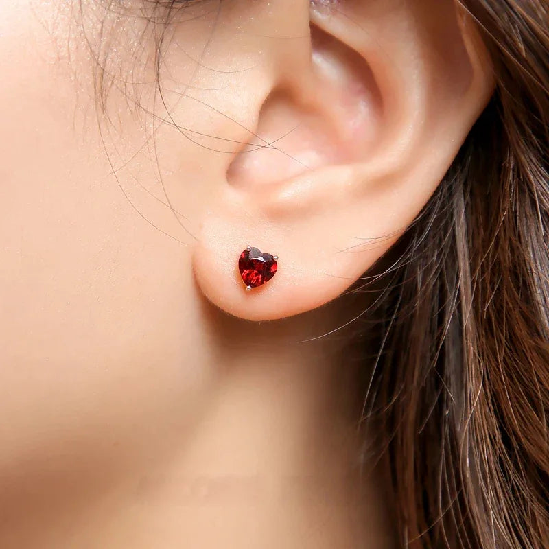 Heart-Cut Garnet Stud Earrings worn on the hand in a close-up