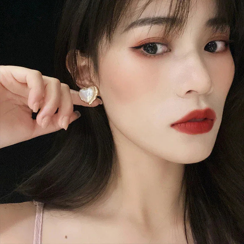 Heart-Shaped Pearl Stud Earrings — left-ear worn portrait showing the bold stud scale