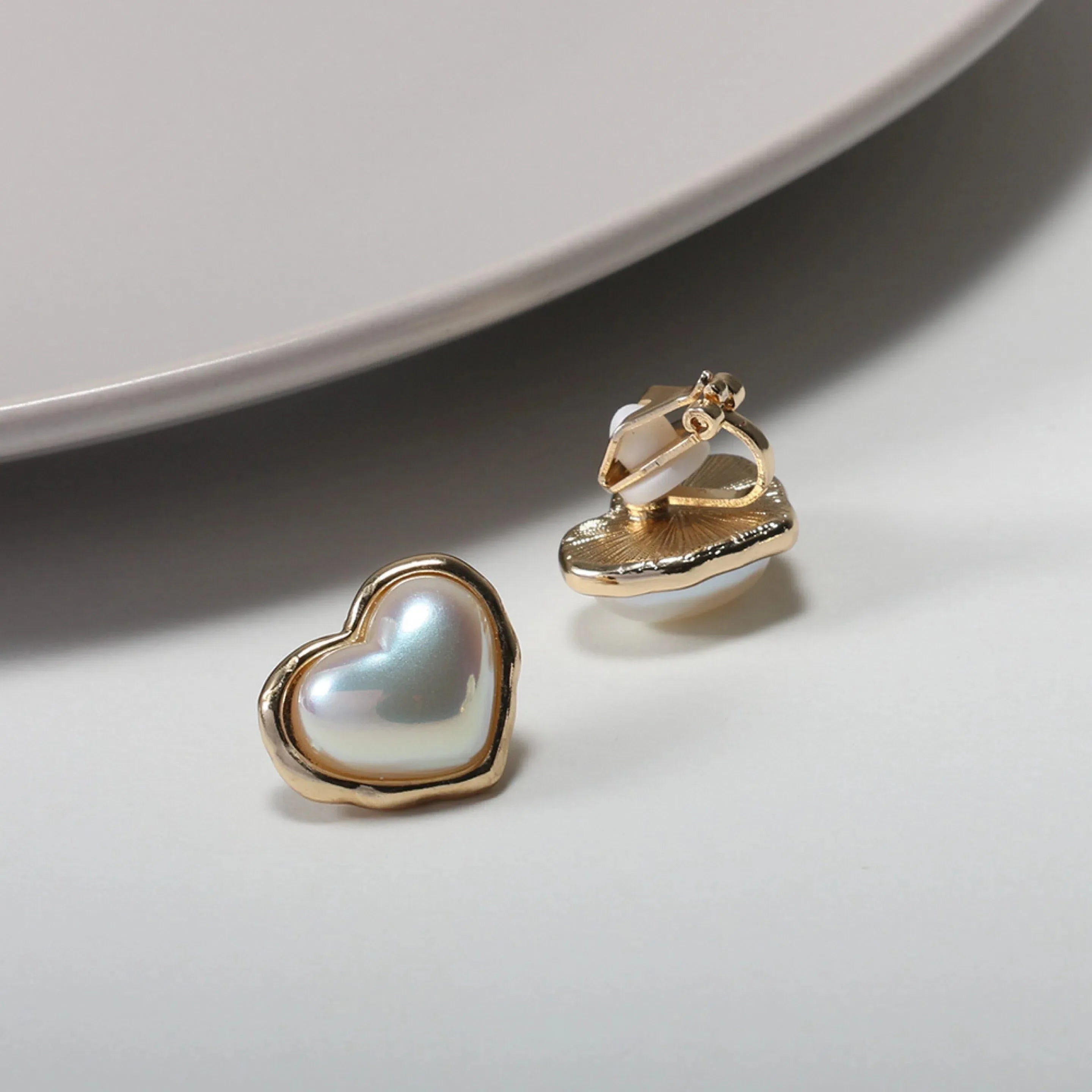 Heart-Shaped Pearl Stud Earrings — angled view showing a hinged clip-style back