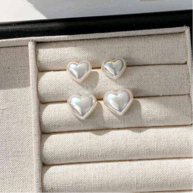 Iridescent Pearl Heart Stud Earrings — small and large size pairs displayed together in a beige jewelry tray
