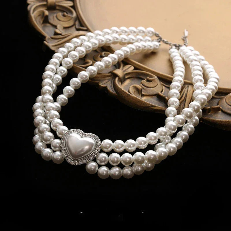 Triple-Strand Pearl Heart Choker Necklace — angled product view on a decorative surface
