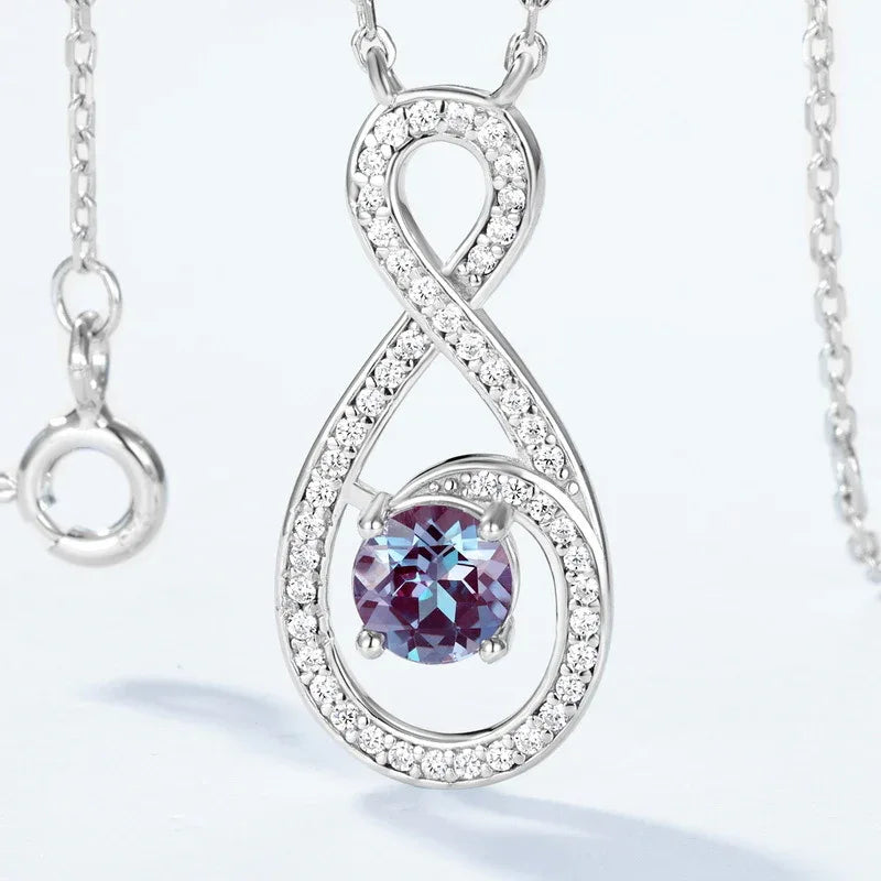Infinity teardrop necklace with a round Alexandrite, close-up showing the setting and decorative accents
