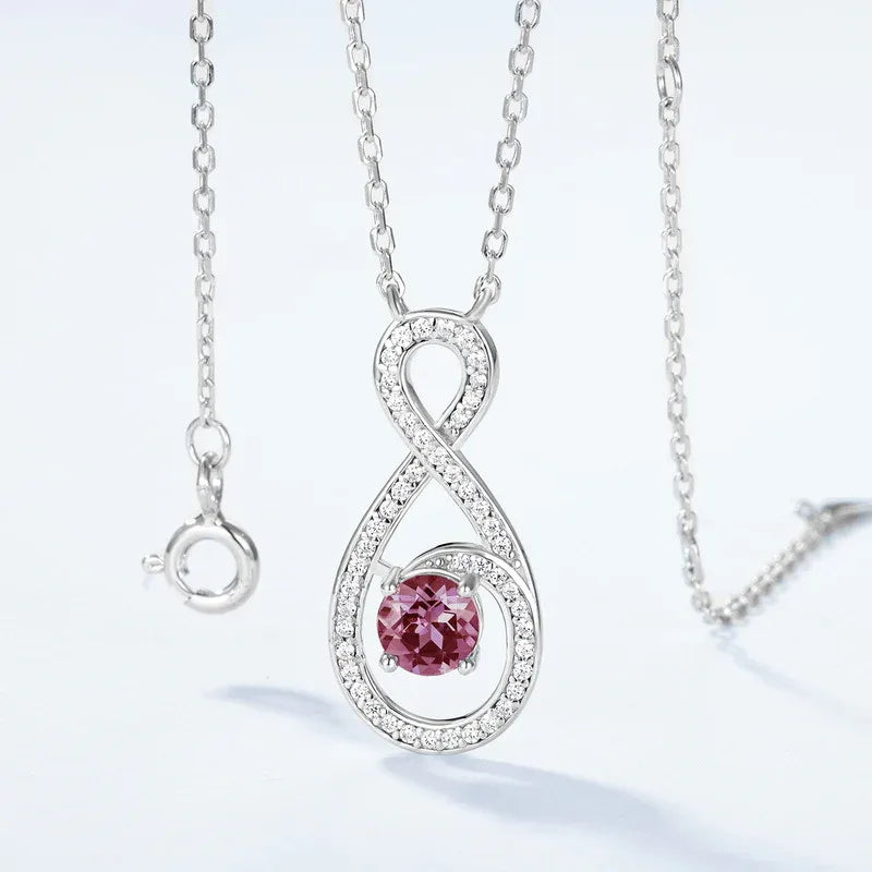 Infinity teardrop necklace with a round Alexandrite, pink-toned Alexandrite view under alternate lighting