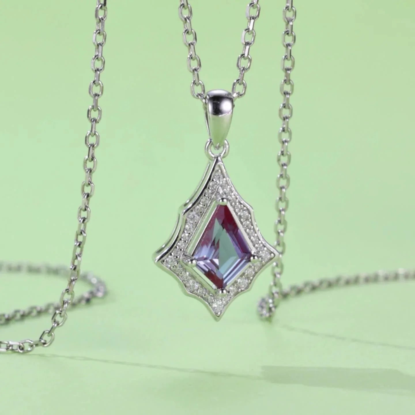 Kite-cut Alexandrite openwork pendant necklace, angled product view on a colored background