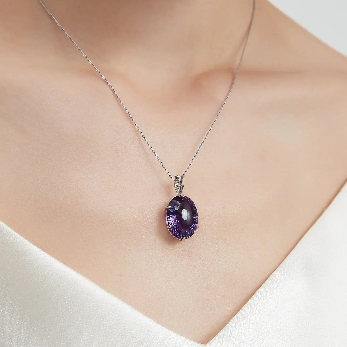 large oval amethyst pendant necklace worn at the neckline in a close-up