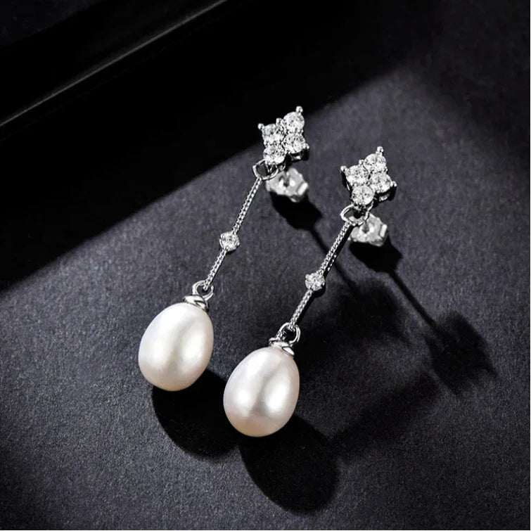 Teardrop Pearl Linear Earrings in Platinum-Plated S925 Silver — pair displayed on a dark fabric surface