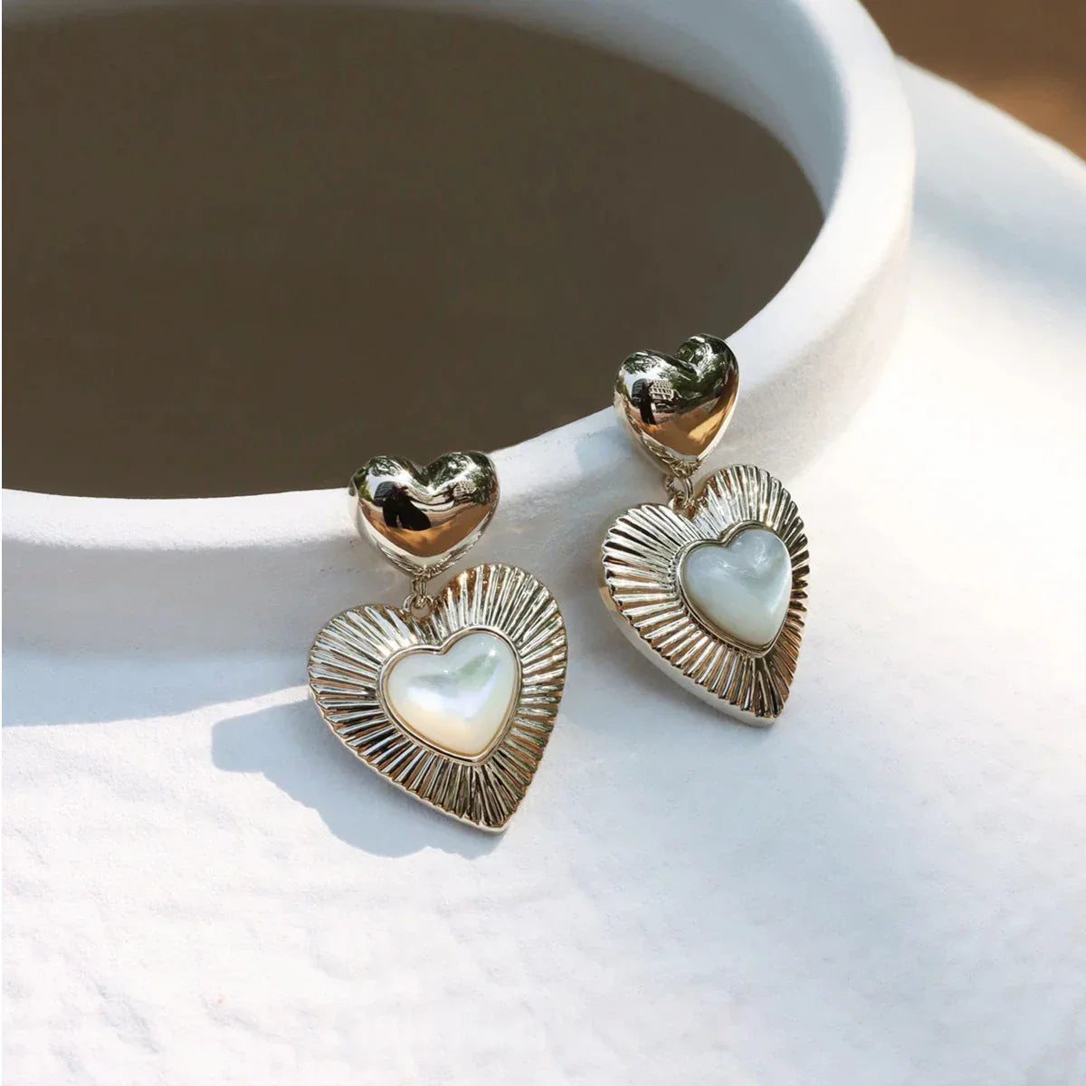 Double-Heart Pearl Drop Earrings — earrings displayed on a white circular stand