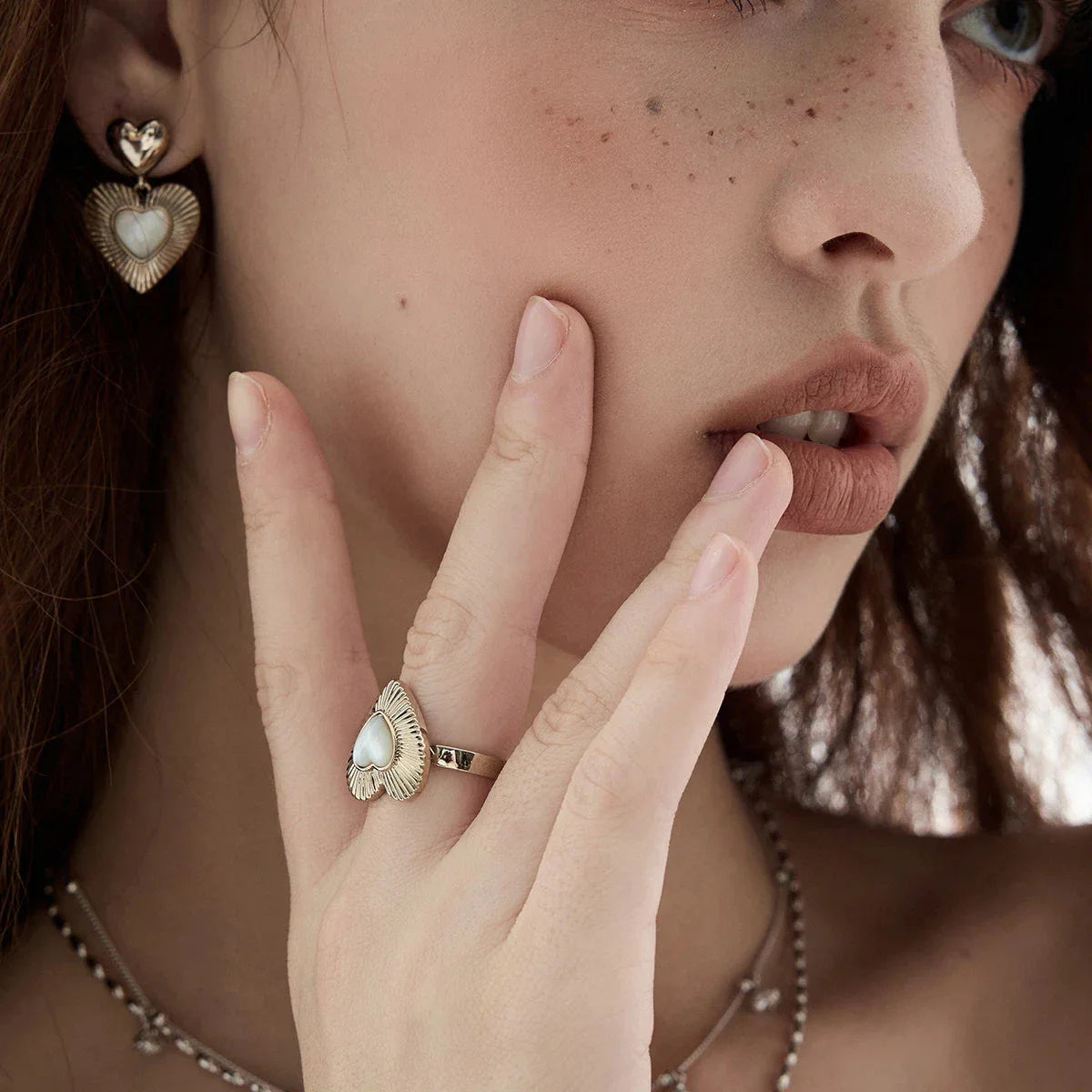 Ridged Pearl Heart Open Ring — hand-worn portrait beside the model's face