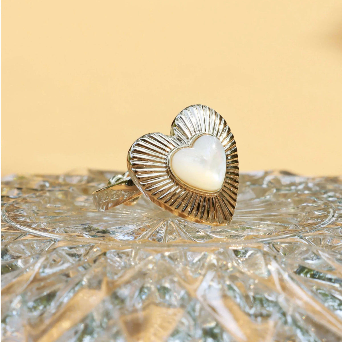 Ridged Pearl Heart Open Ring — ring displayed on a textured gold surface