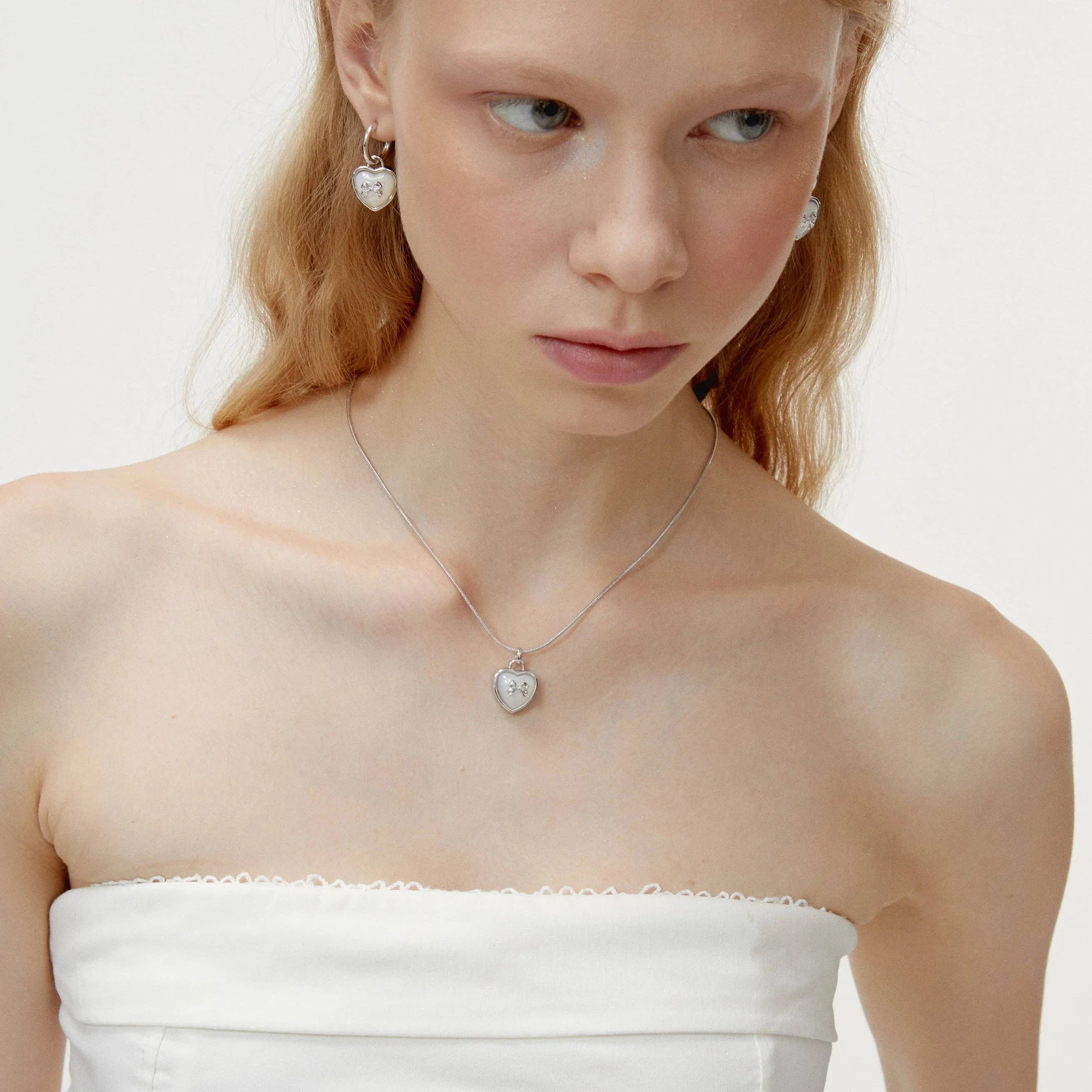 Pearl Heart Pendant Necklace with Bow Detail — front model portrait wearing the necklace