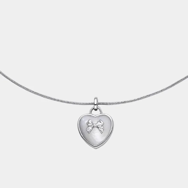 Pearl Heart Pendant Necklace with Bow Detail — isolated front close-up of the heart pendant with raised bow on a fine