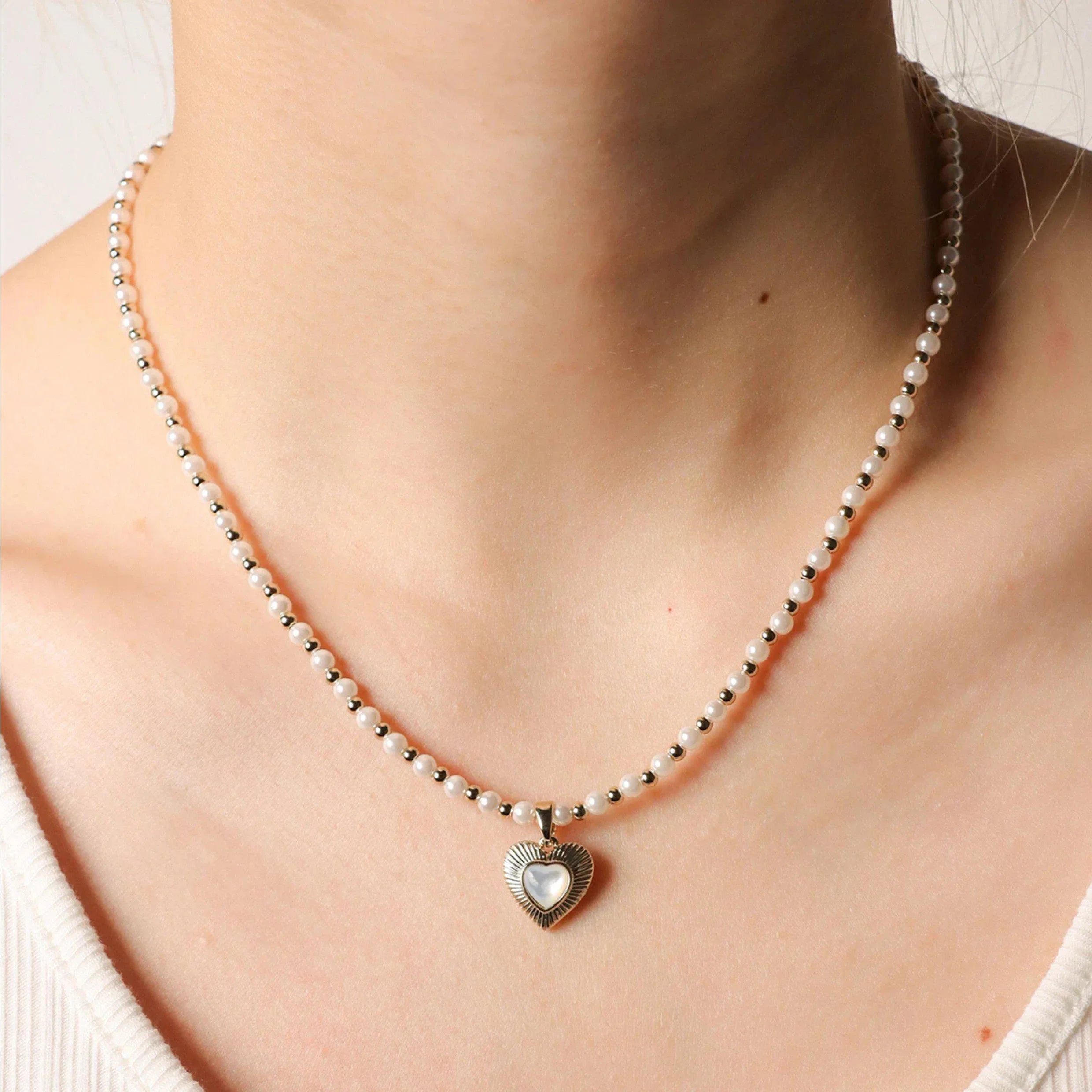 Pearl Bead Necklace with Petite Ridged Heart — neckline-worn view with the heart centered