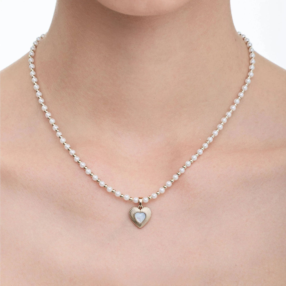 Pearl Bead Necklace with Petite Ridged Heart — front neckline-worn close-up showing the compact heart scale