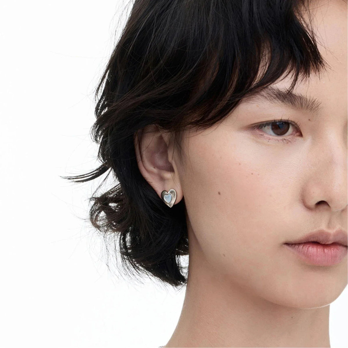 Petite Ridged Pearl Heart Stud Earrings — front model portrait wearing the earrings