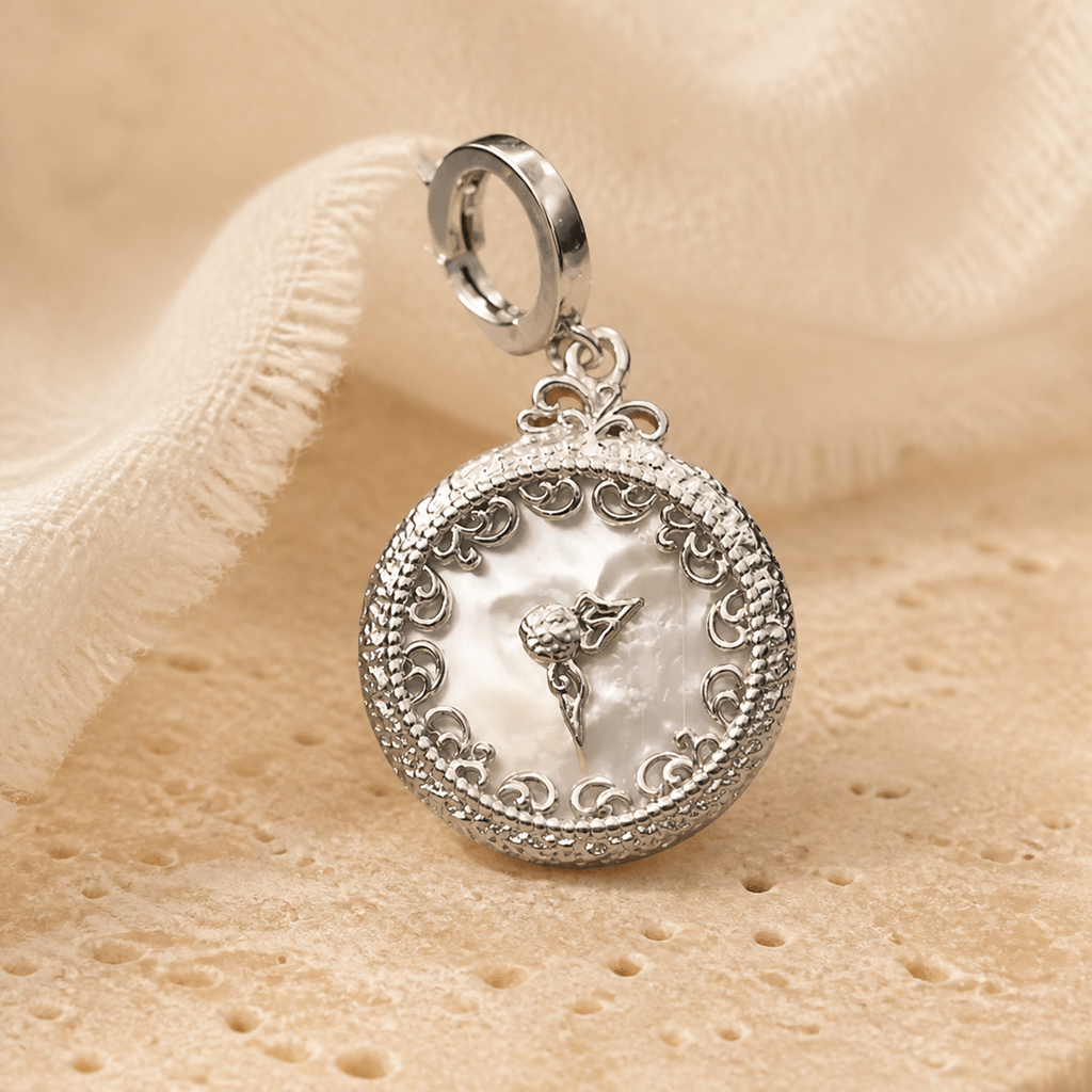 Silver mother-of-pearl clock pendant displayed on warm beige stone with an ivory linen backdrop