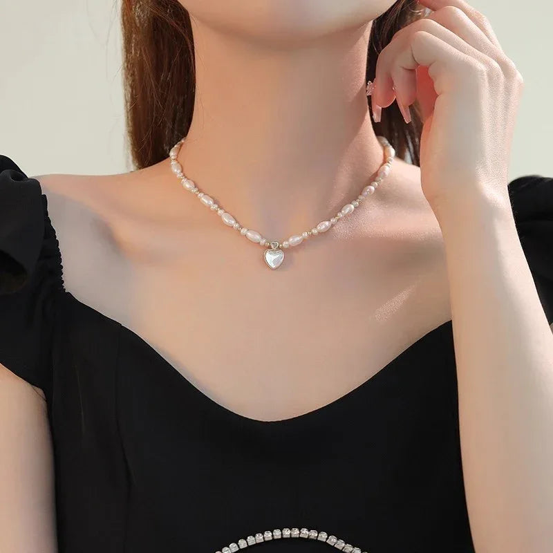 Baroque Pearl Heart Pendant Necklace — front neckline-worn view over a black off-shoulder top