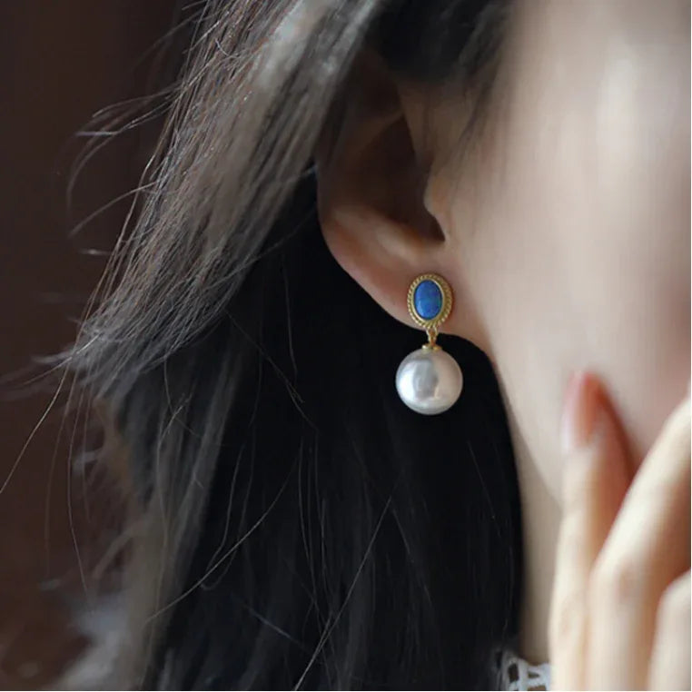 Blue Opal and Pearl Drop Earrings — left-ear worn close-up partly framed by dark hair