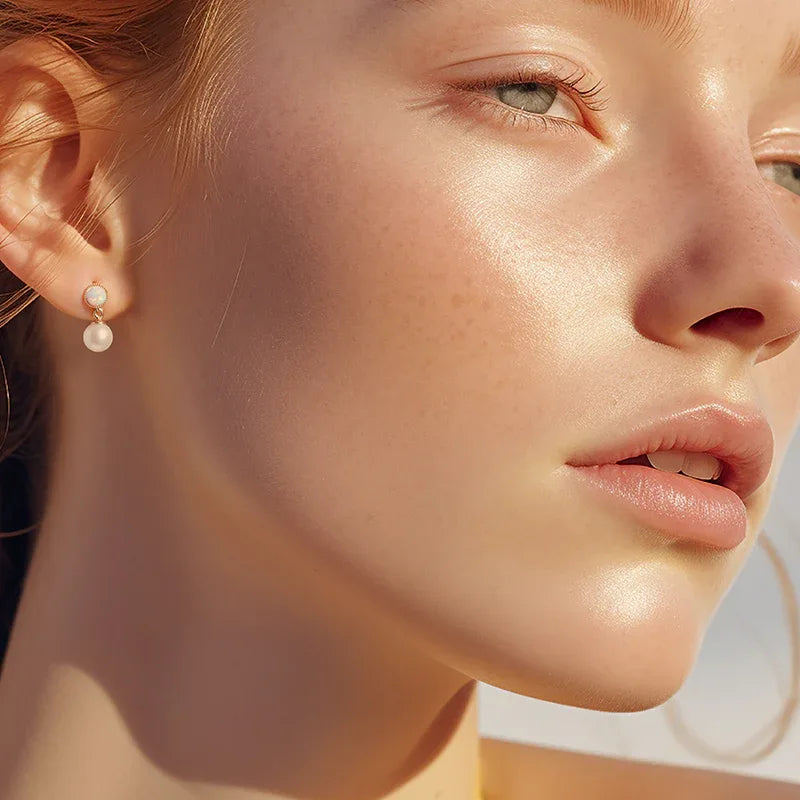 White Opal and Pearl Drop Earrings — left-ear worn portrait in warm sunlight
