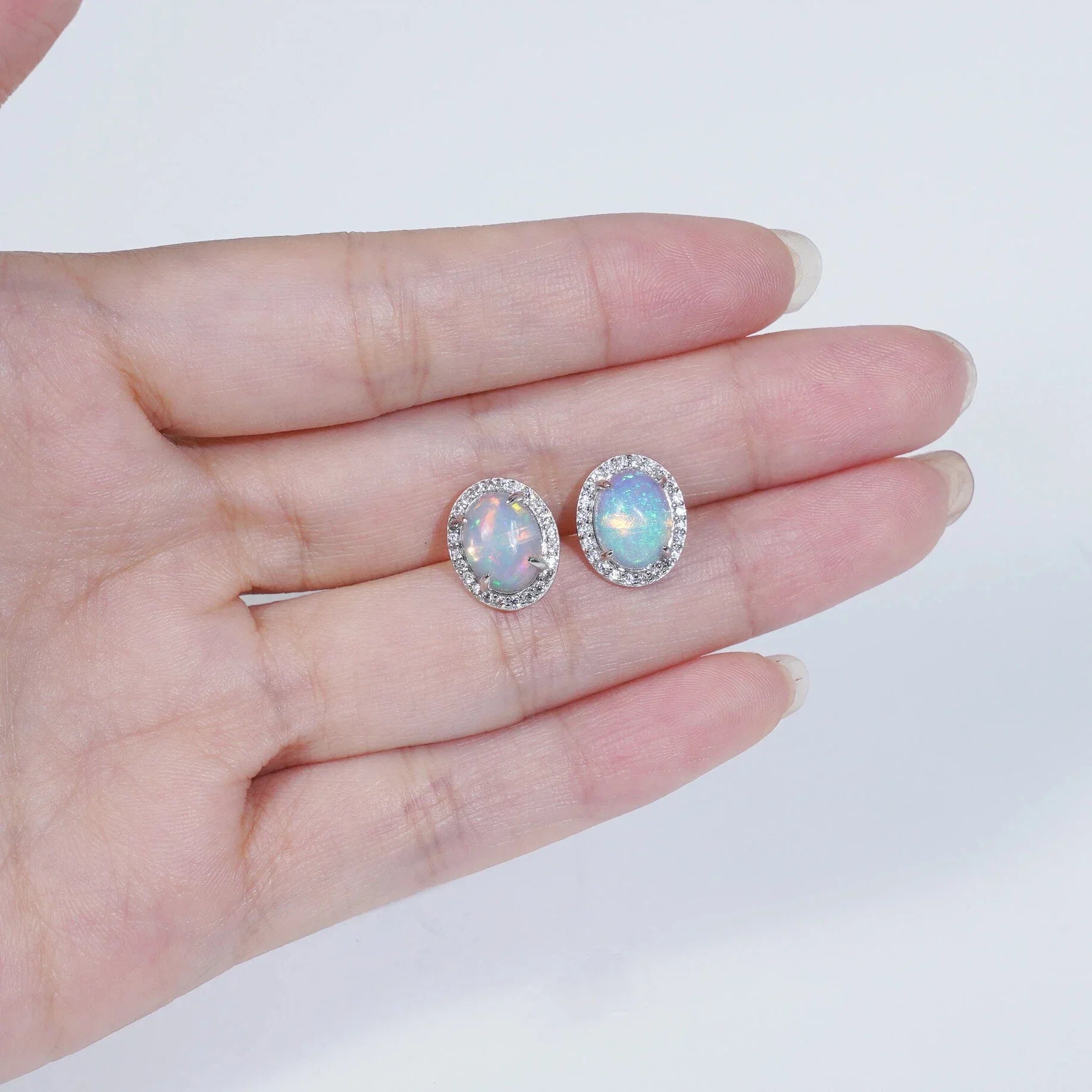 Opal Round Halo Stud Earrings worn on the hand