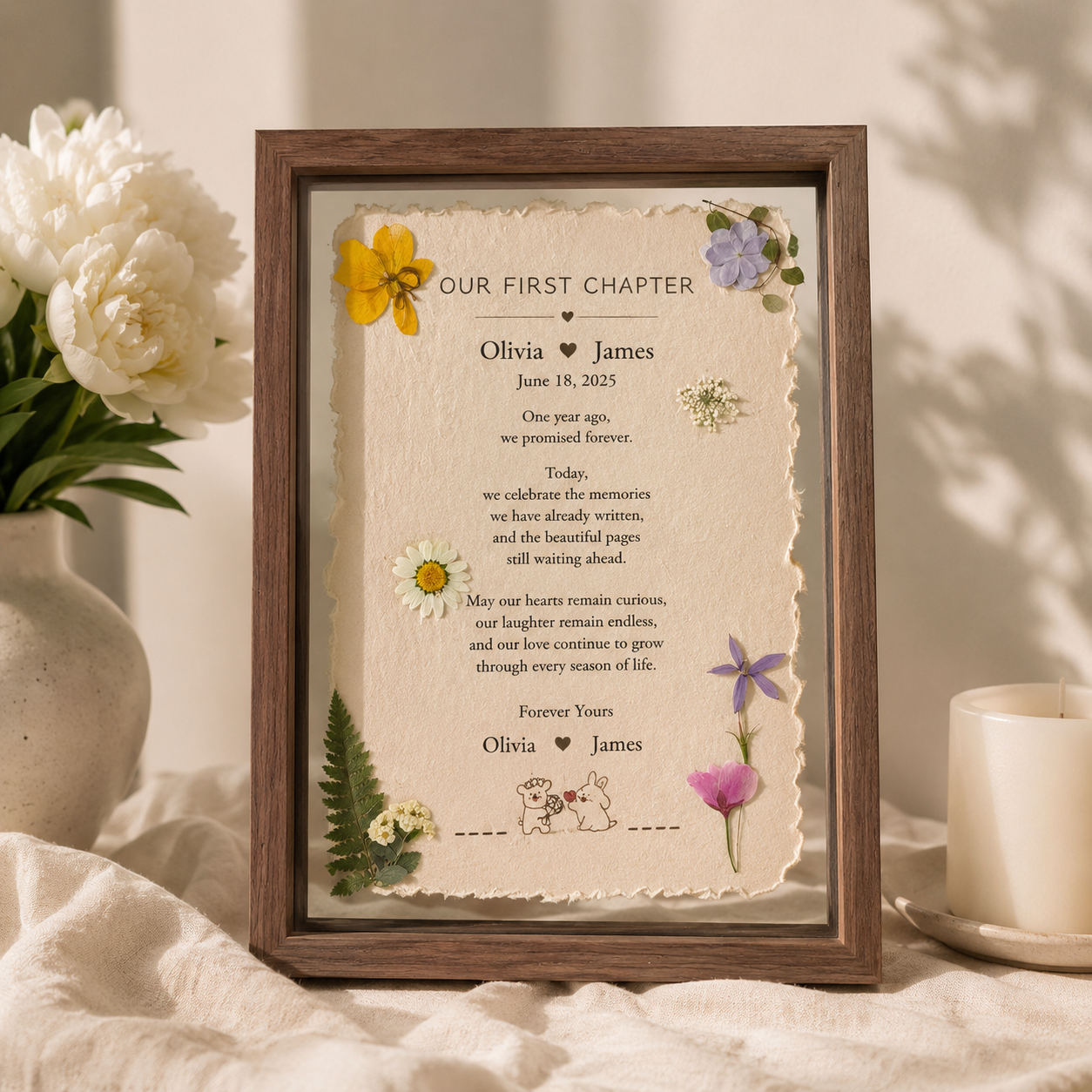 Our First Chapter personalized floating botanical frame displayed on a bright living room sideboard beside white ceramic