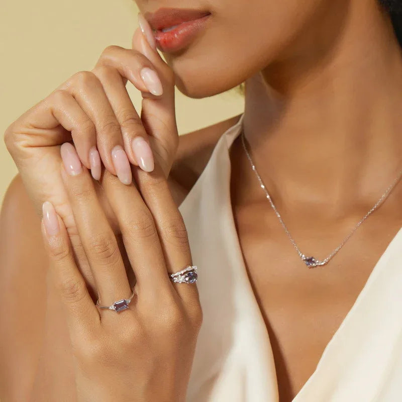 Oval Alexandrite floral three-band ring with clear accents, shown worn by a model for scale