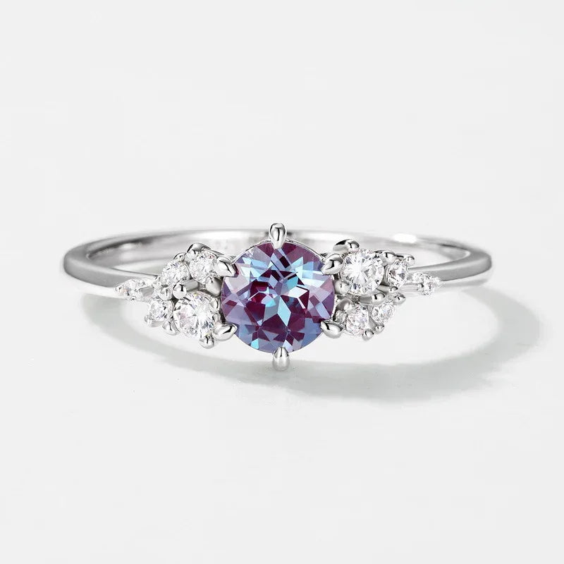 Oval Alexandrite ring with clear-stone side clusters, center stone close-up on a white background