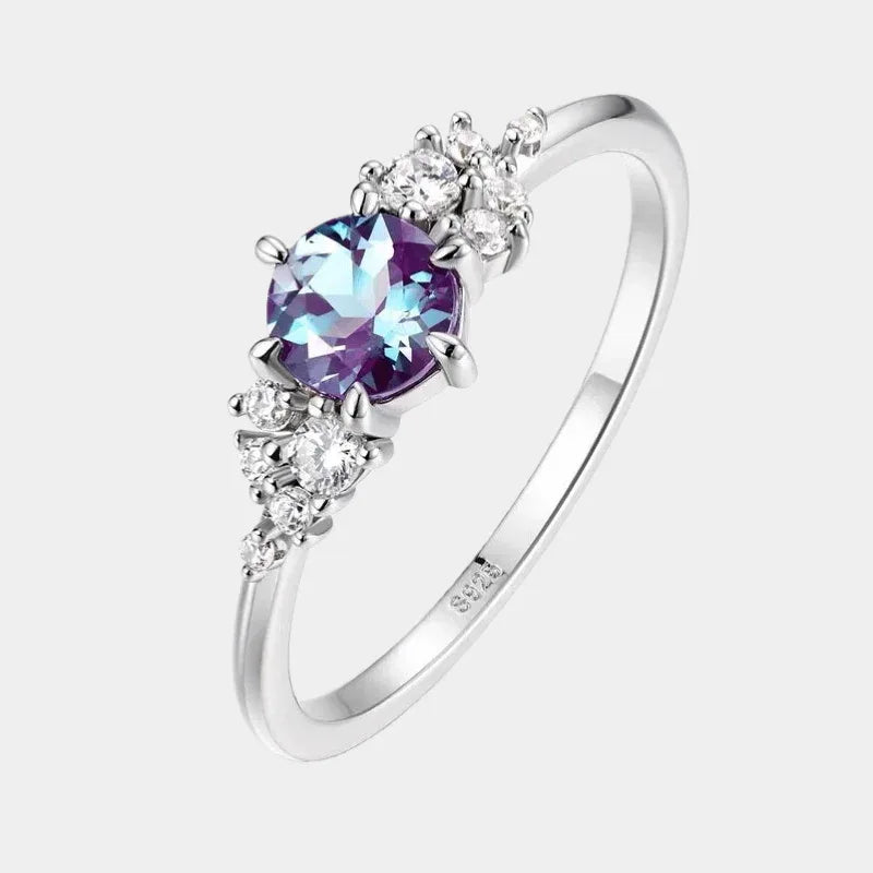 Oval Alexandrite ring with clear-stone side clusters, front product view on a white background