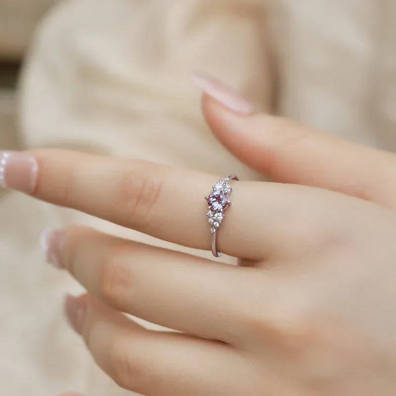 Oval Alexandrite ring with clear-stone side clusters, shown worn in a close lifestyle view