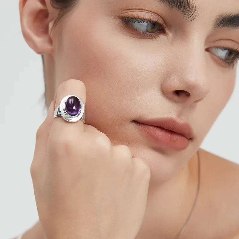 oval amethyst wide-band ring worn on the hand in a close-up