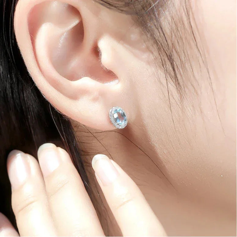 Oval Aquamarine Halo Stud Earrings worn on the ear from a second angle