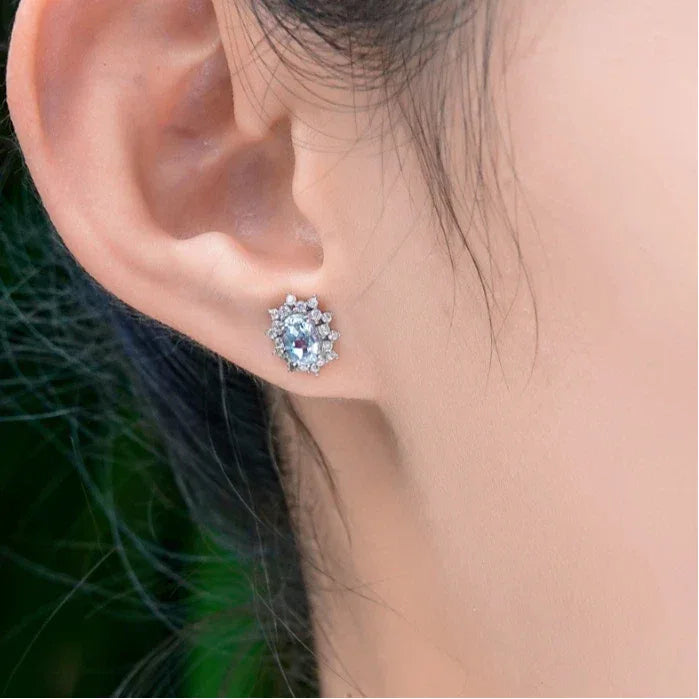 Oval Aquamarine Starburst Halo Stud Earrings worn on the ear from a second angle