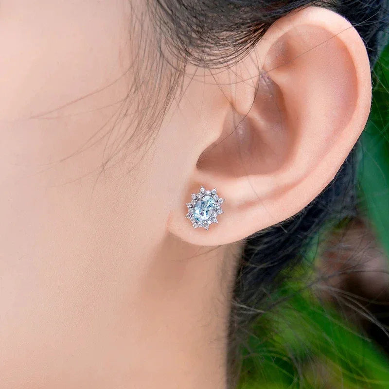 Oval Aquamarine Starburst Halo Stud Earrings worn on the ear in a close-up