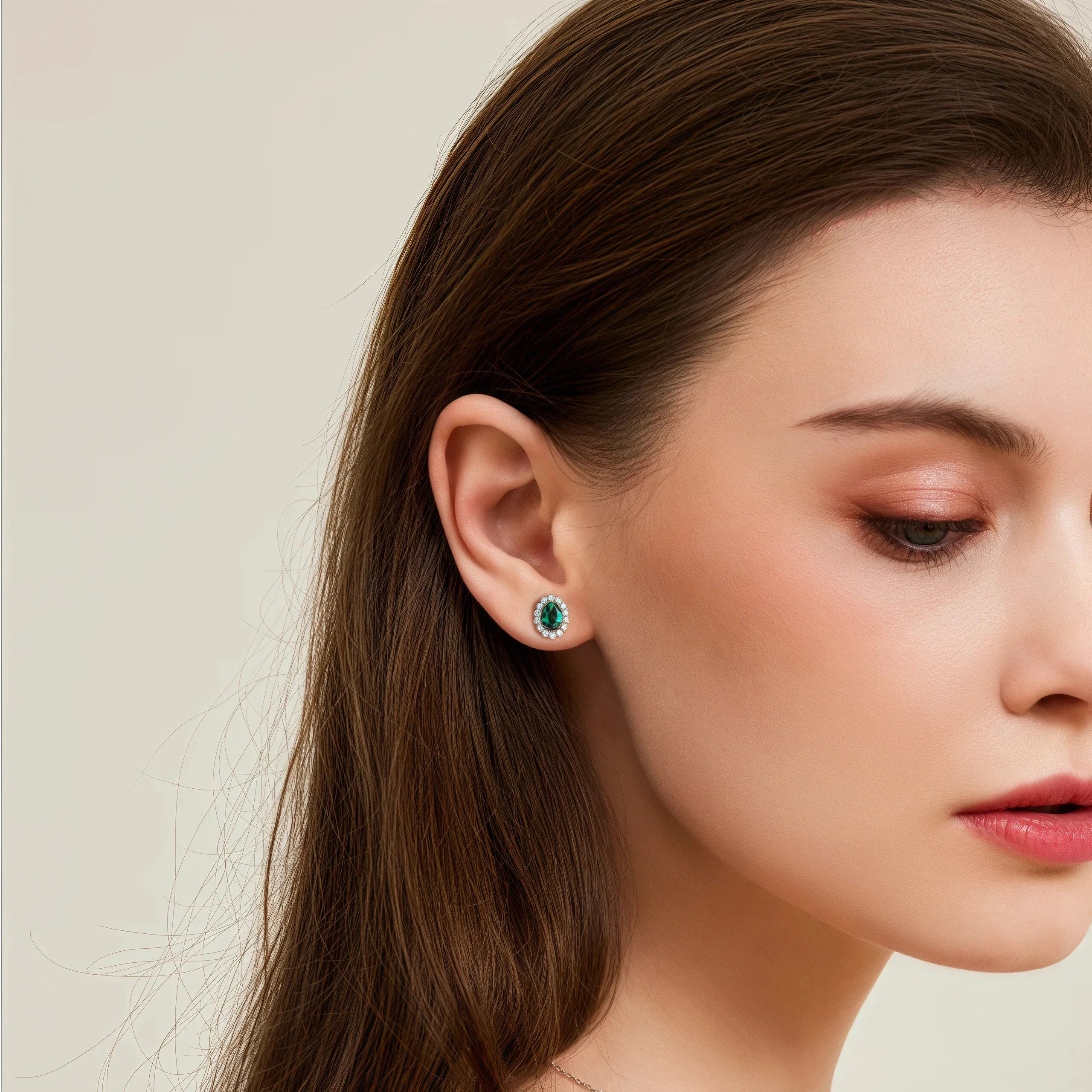 Oval Emerald Halo Stud Earrings styled ear view showing scale