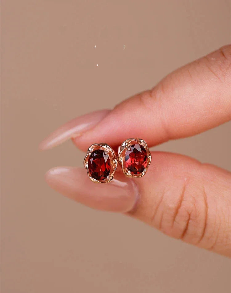 Oval Garnet Bezel Stud Earrings side view held between the fingers