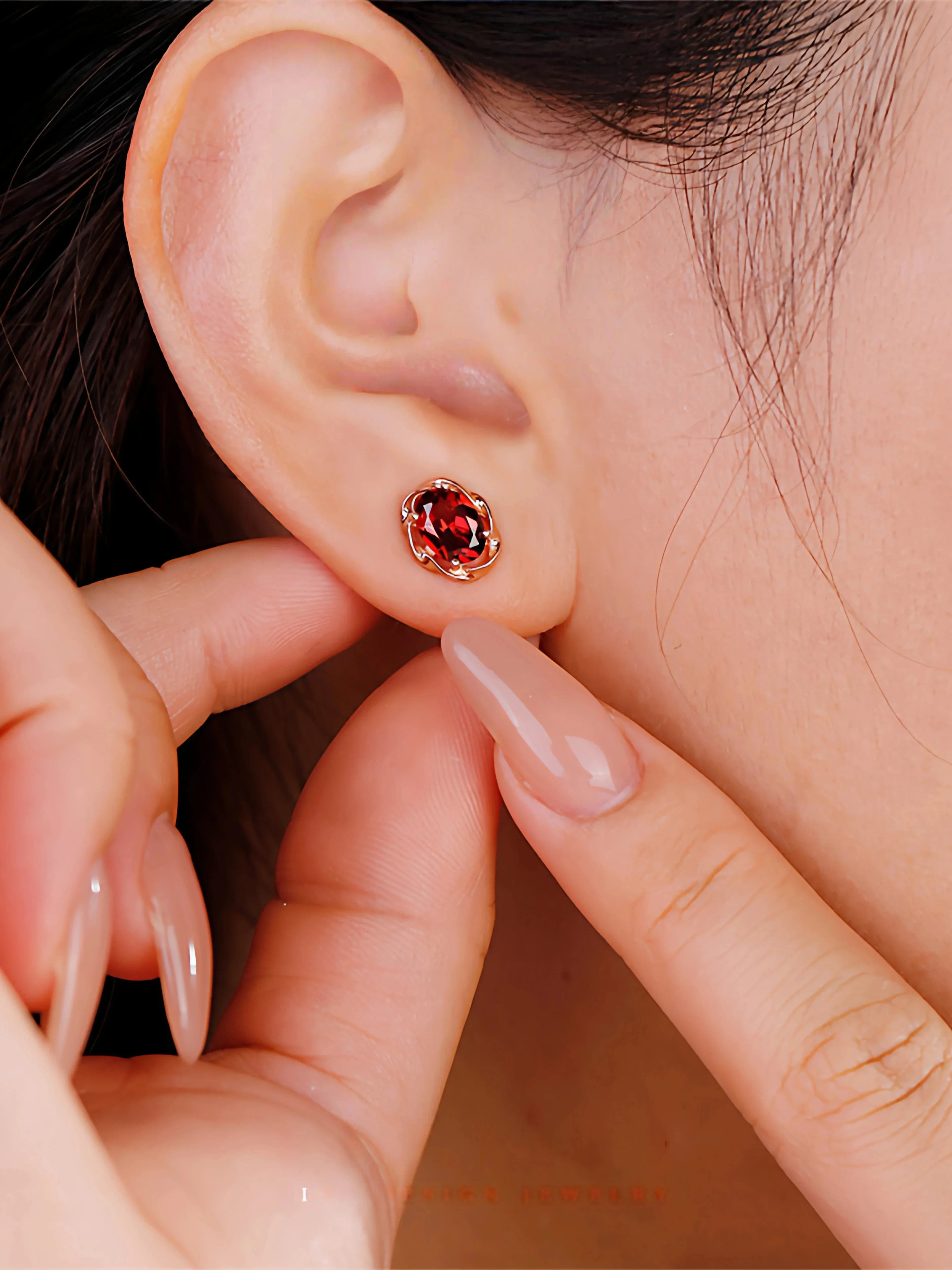 Oval Garnet Bezel Stud Earrings worn on the hand from a second angle