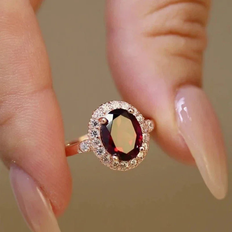 Oval Garnet Halo Adjustable Ring side view held between the fingers