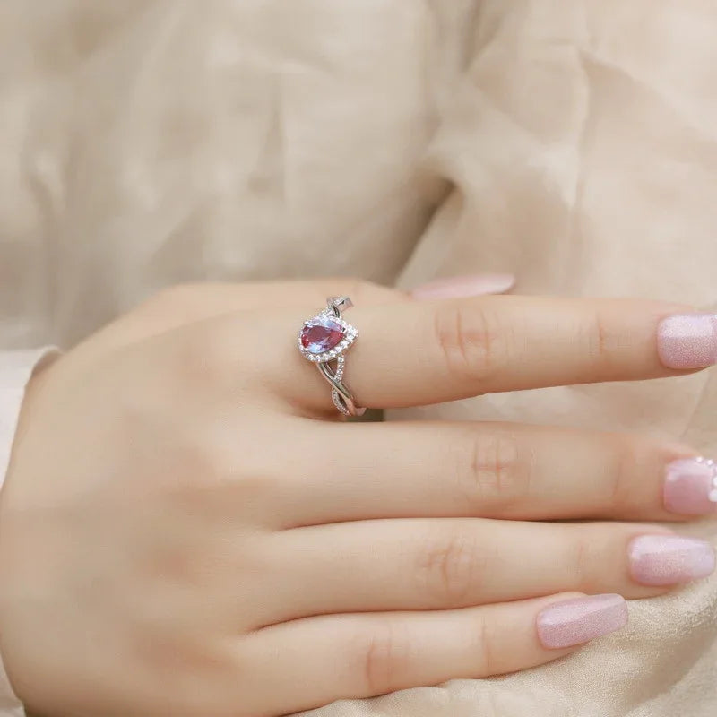 Pear-cut Alexandrite halo ring with a sweeping bypass band, alternate shown worn in a close lifestyle view