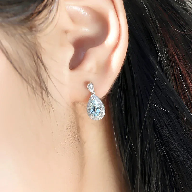Pear-Cut Aquamarine Halo Drop Earrings worn on the ear from a second angle