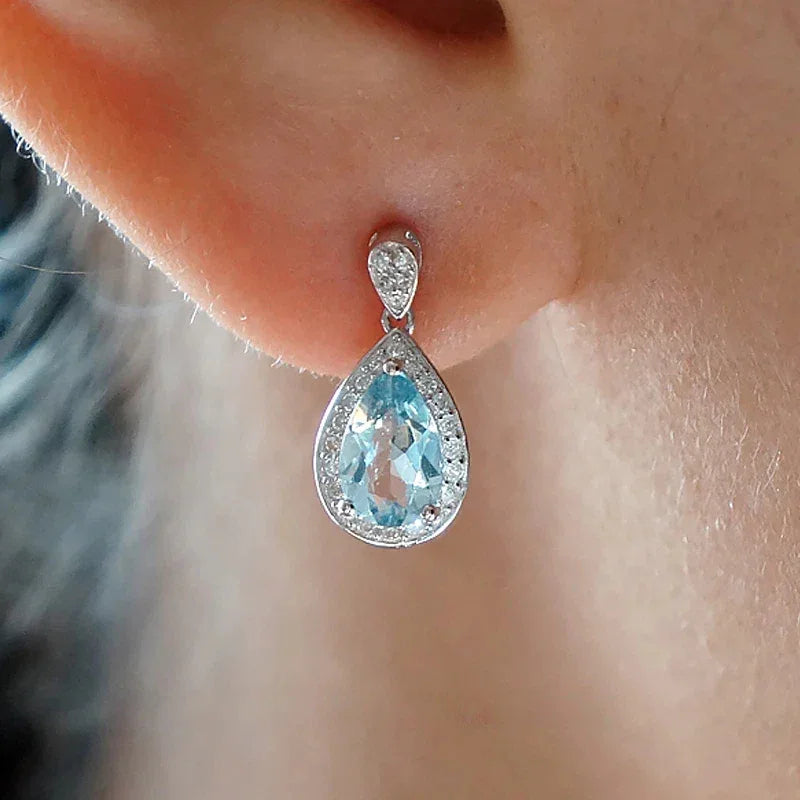 Pear-Cut Aquamarine Halo Drop Earrings worn on the ear in a close-up