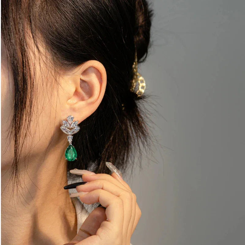 Pear-Cut Emerald Floral Drop Earrings worn on the ear in a close-up