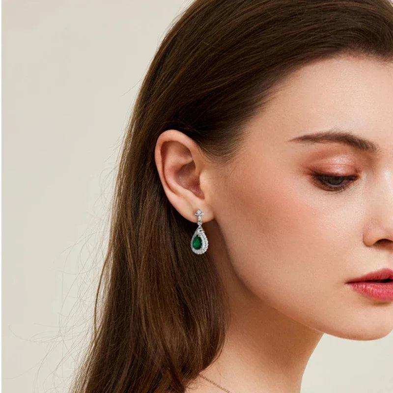 Pear-Cut Emerald Halo Drop Earrings worn on the ear from a second angle