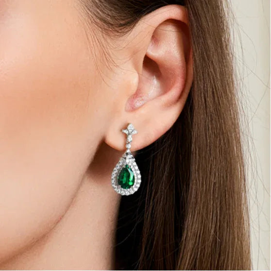 Pear-Cut Emerald Halo Drop Earrings worn on the ear in a close-up