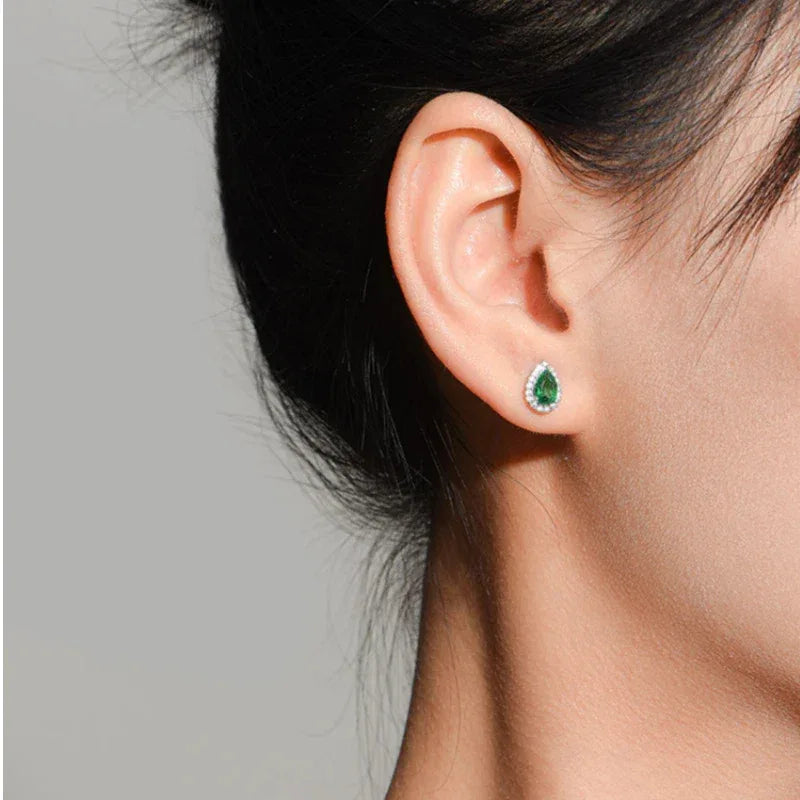 Pear-Cut Emerald Halo Stud Earrings worn on the ear from a second angle