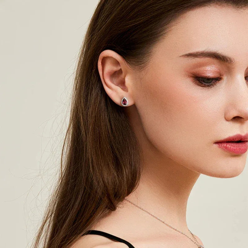 Pear-Cut Garnet Halo Stud Earrings side view held between the fingers