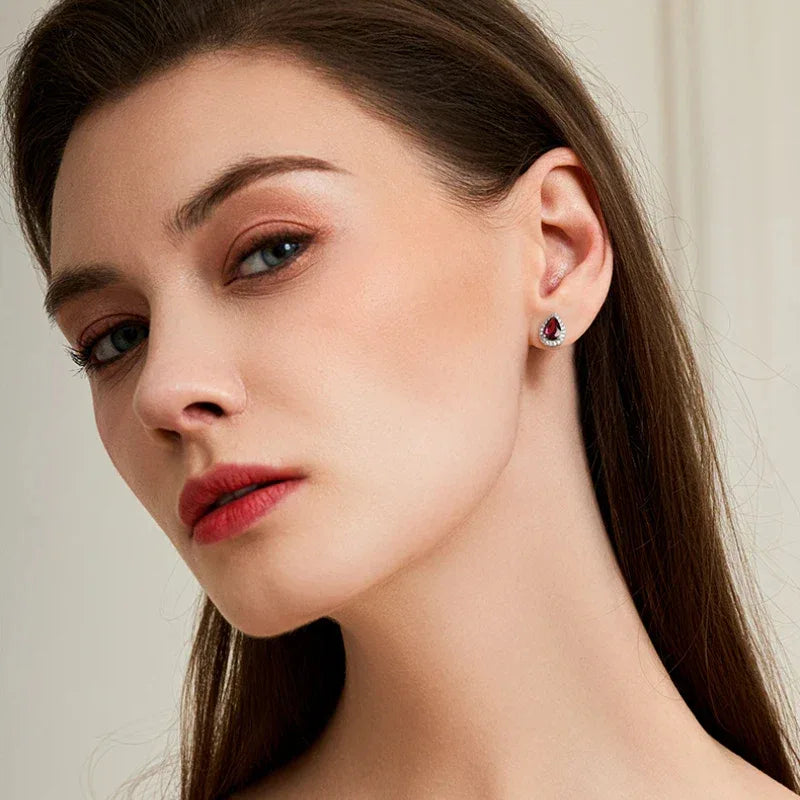 Pear-Cut Garnet Halo Stud Earrings worn on the hand from a second angle