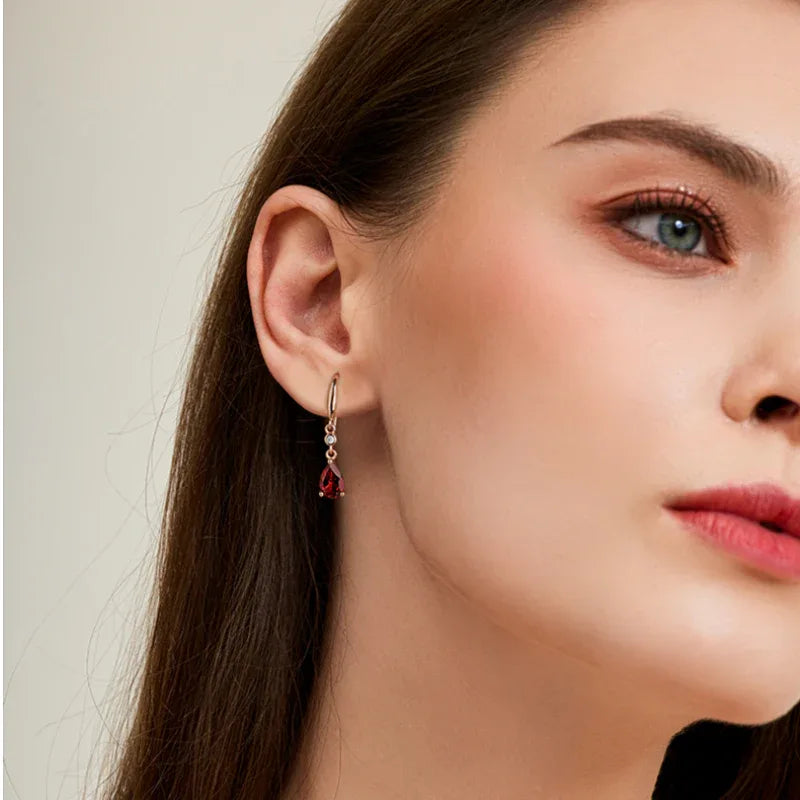 Pear-Cut Garnet Hook Drop Earrings worn on the hand in a close-up